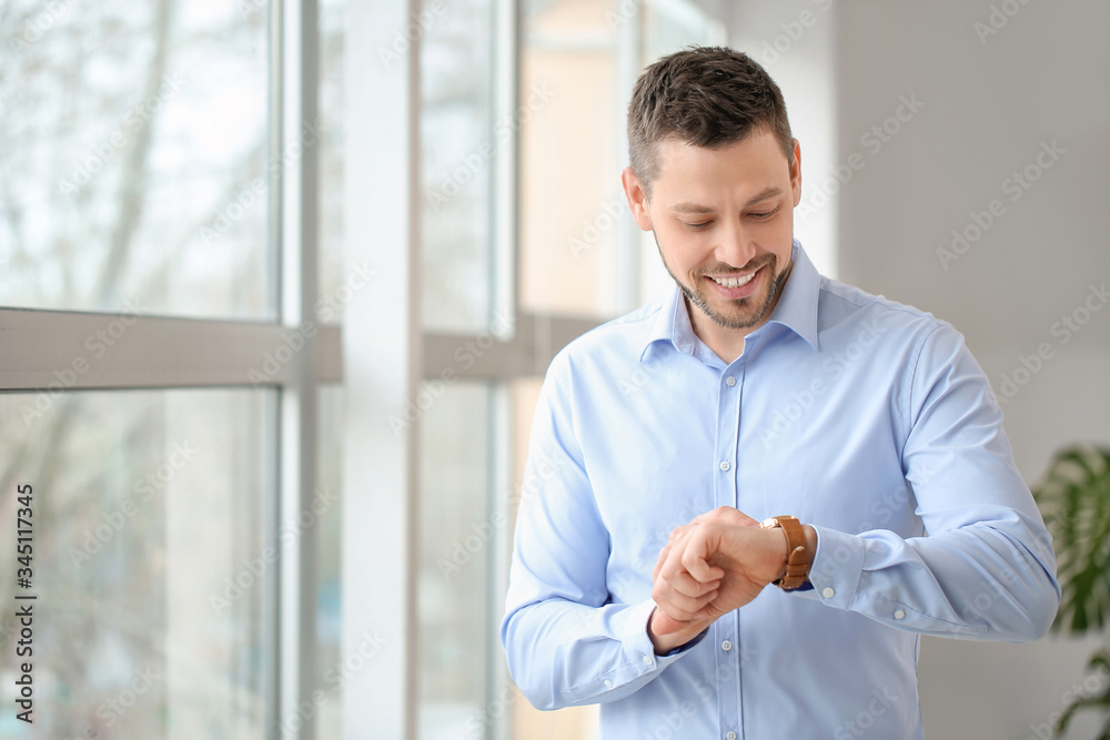 Portrait of handsome businessman looking at his watch in office