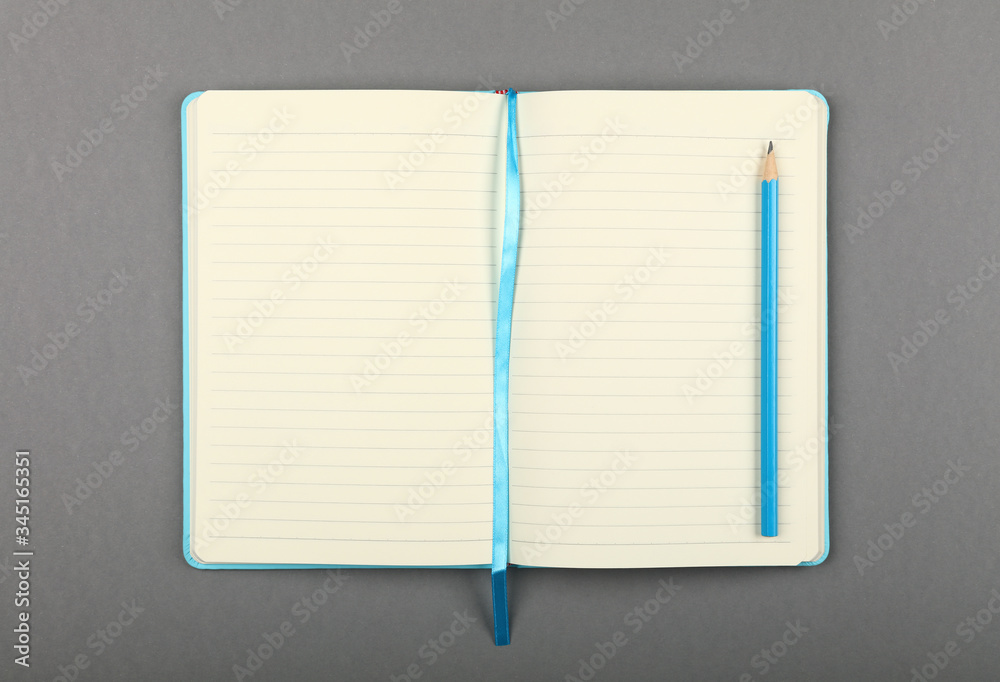 Open blue notebook with pencil over grey