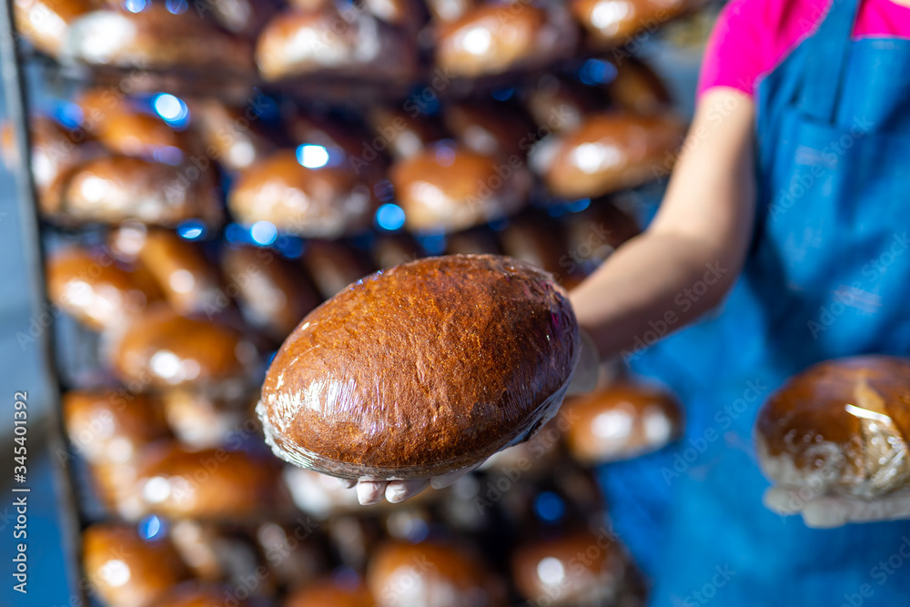 Bread in the hands of a baker on the background of an industrial oven. Industrial bread production