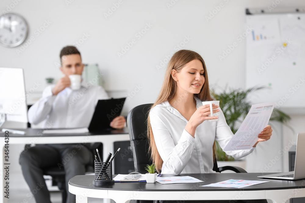 Young woman drinking coffee while working in office