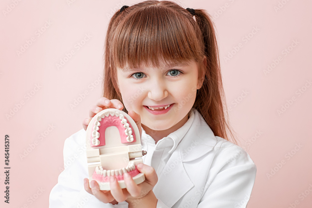 Little dentist with plastic jaw model on color background