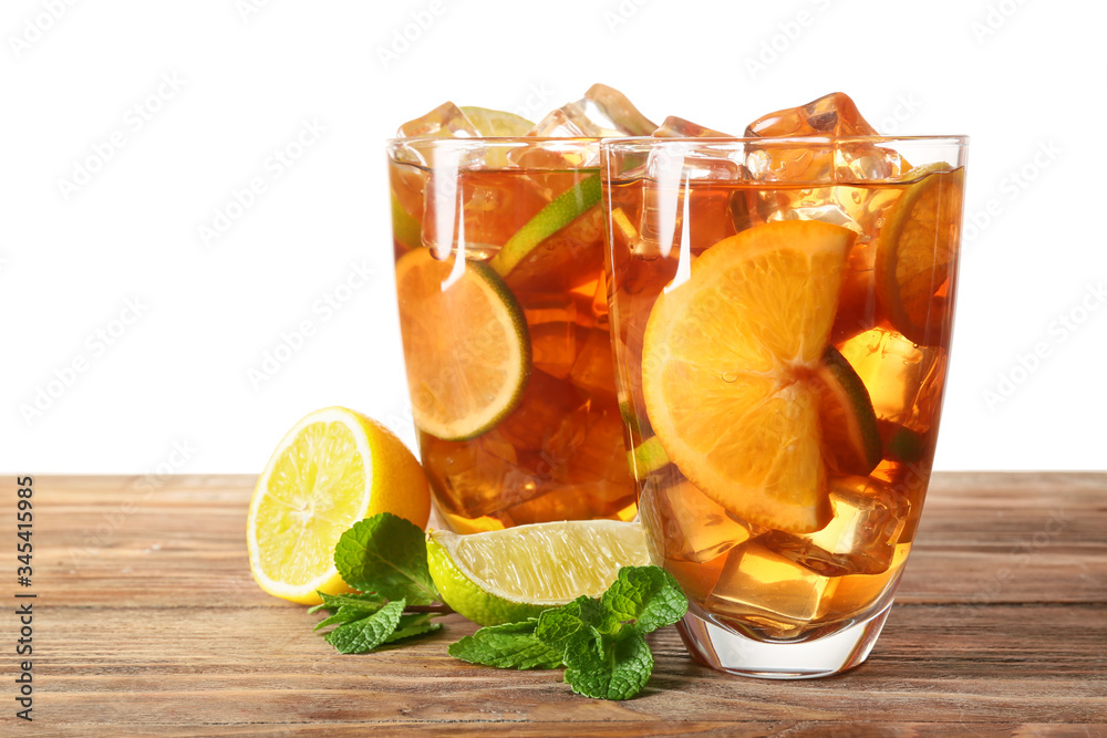 Glasses of tasty cold ice tea on table against white background