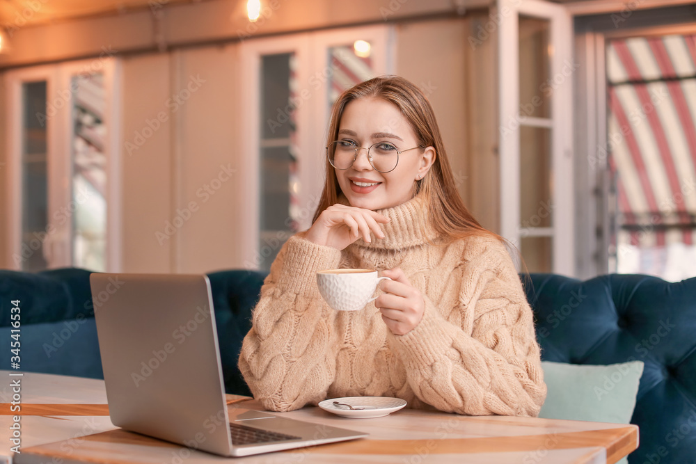 Young businesswoman drinking coffee during work in cafe