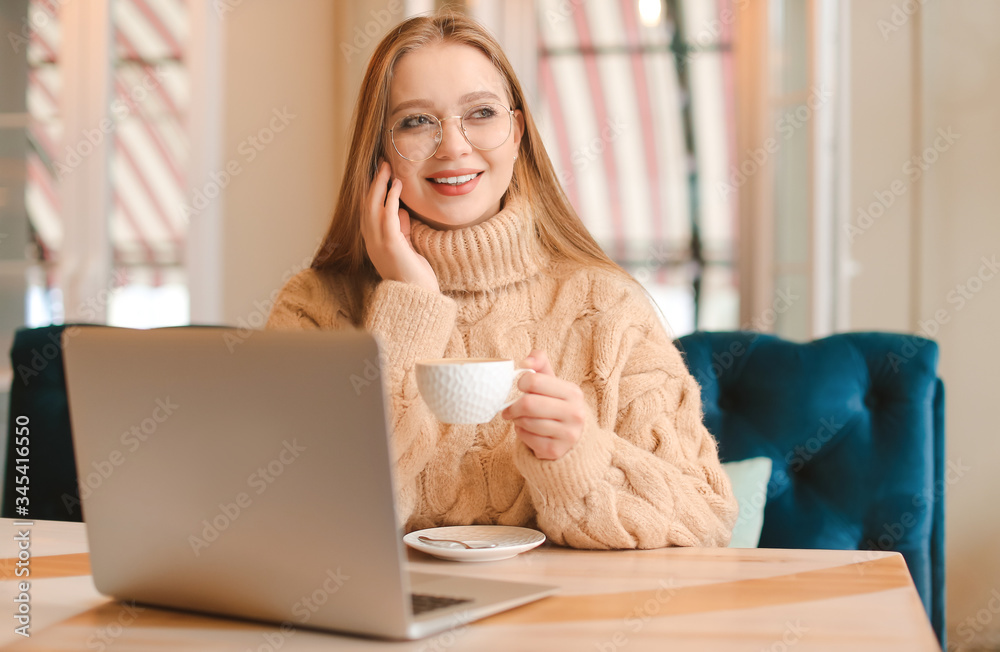 Young businesswoman drinking coffee during work in cafe