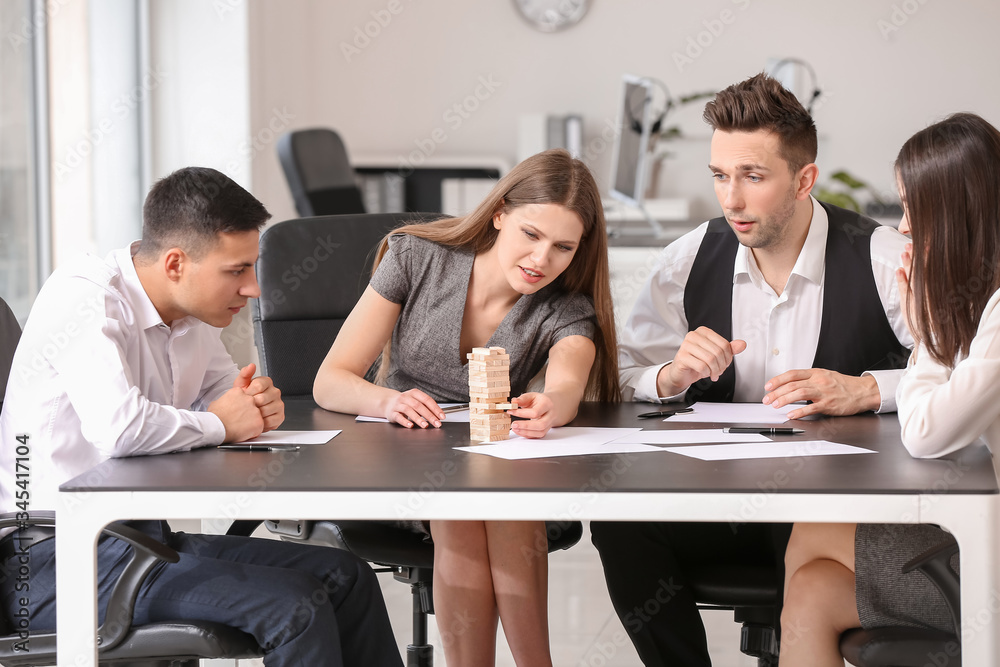 Team of business people playing jenga in office