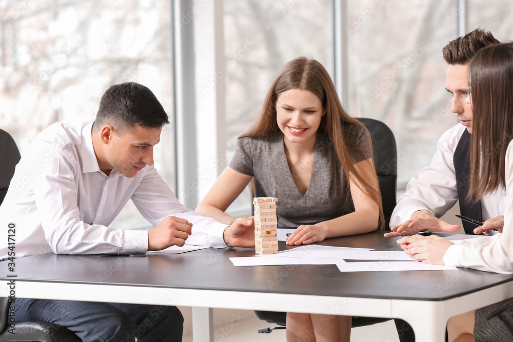 Team of business people playing jenga in office