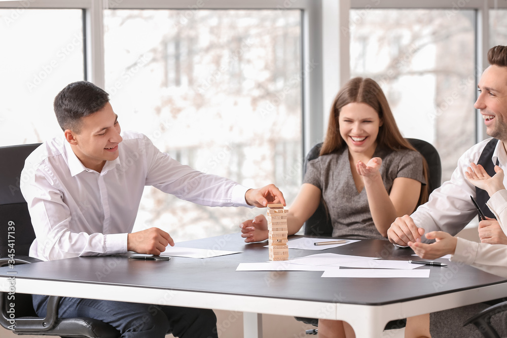 Team of business people playing jenga in office