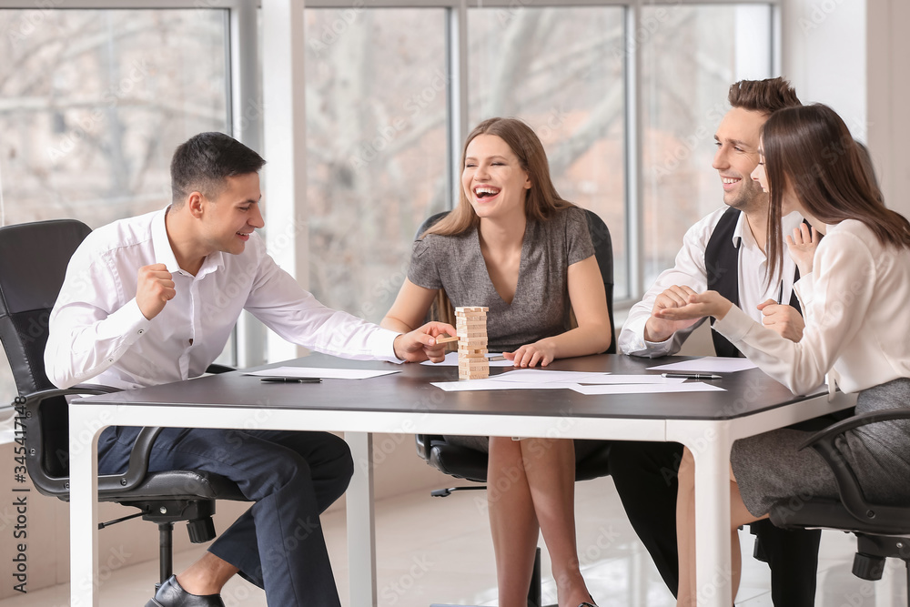 Team of business people playing jenga in office