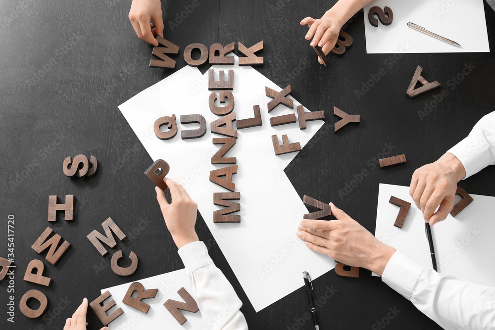 Team of business people composing words from letters in office, top view