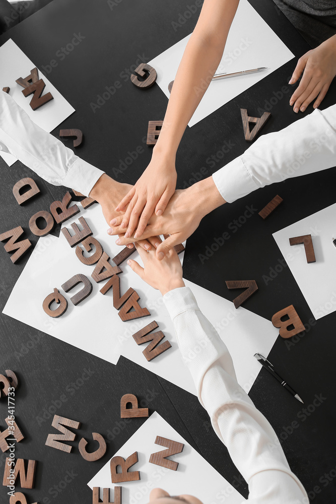 Team of business people putting hands together in office, top view