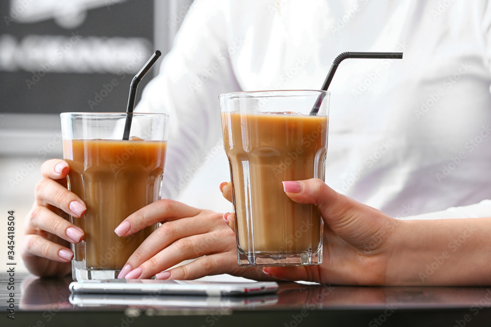 Women with glasses of tasty iced coffee in cafe, closeup