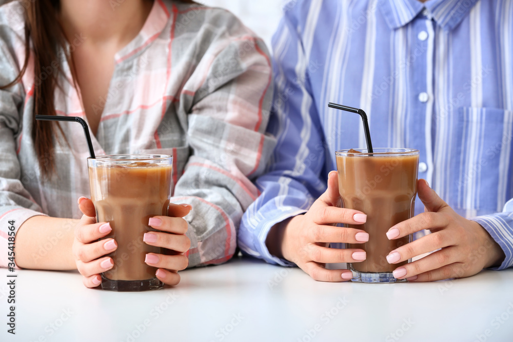 Women with glasses of tasty iced coffee in cafe, closeup