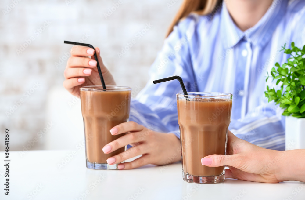 Women with glasses of tasty iced coffee in cafe, closeup