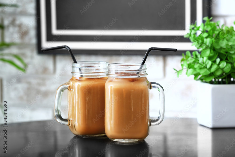 Mason jars of tasty iced coffee on table in cafe