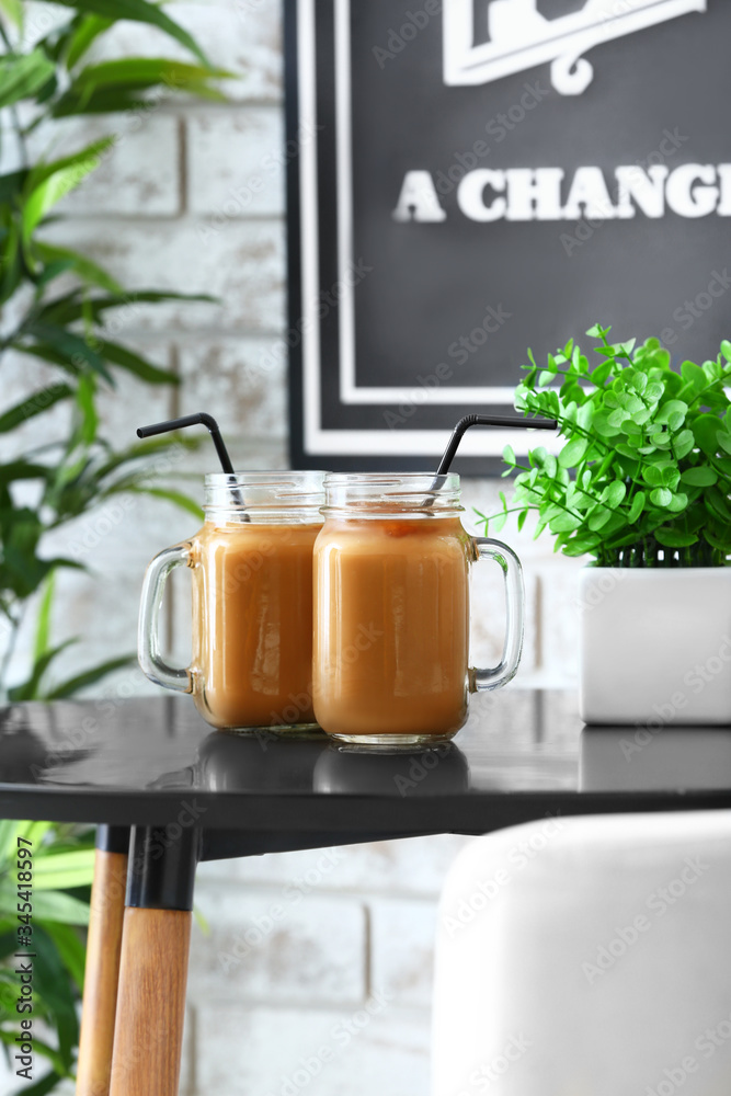 Mason jars of tasty iced coffee on table in cafe