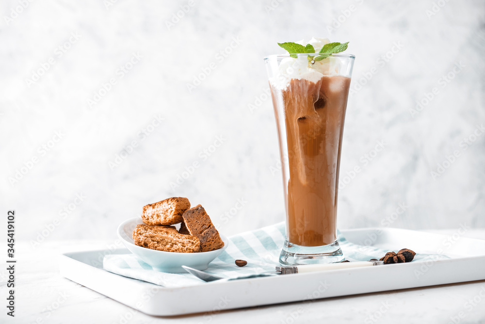 Glass of tasty iced coffee with cookies on table