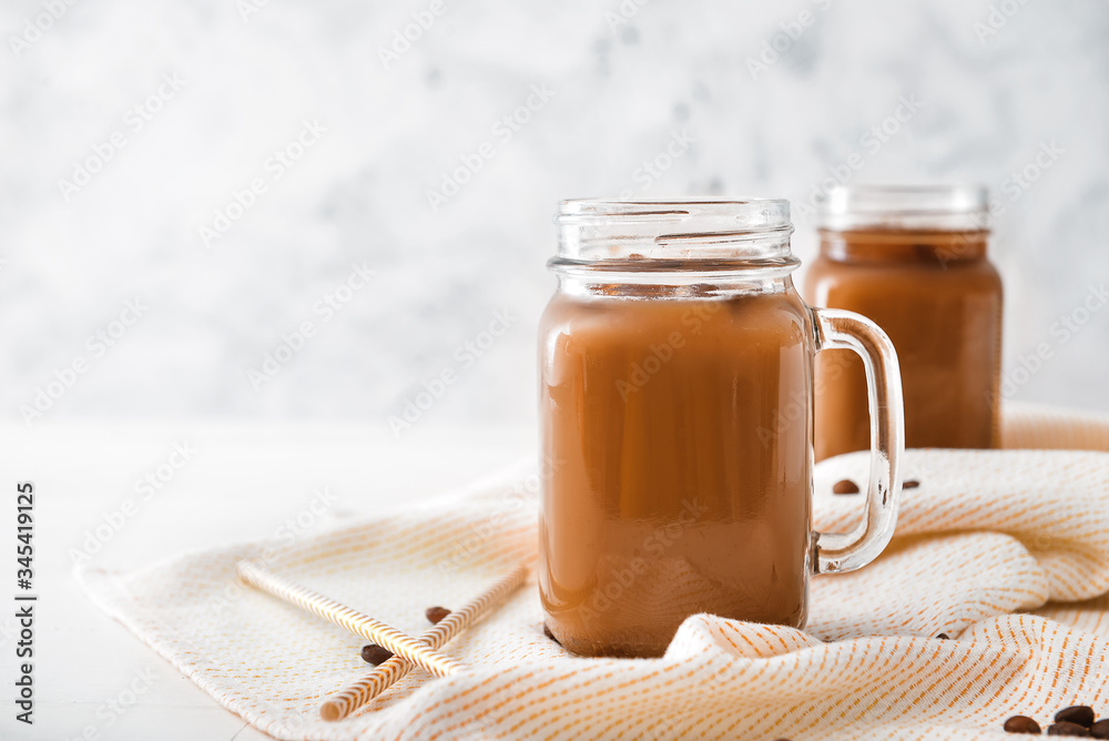 Mason jar of tasty iced coffee on table