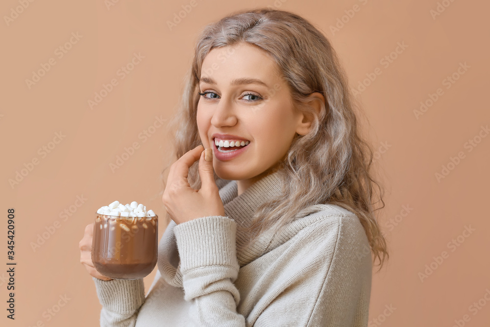 Beautiful young woman with cup of hot chocolate on color background