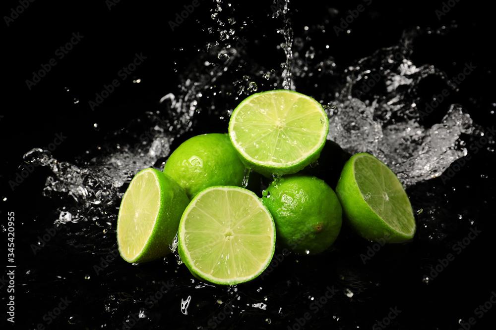 Fresh limes with water splashes on dark background