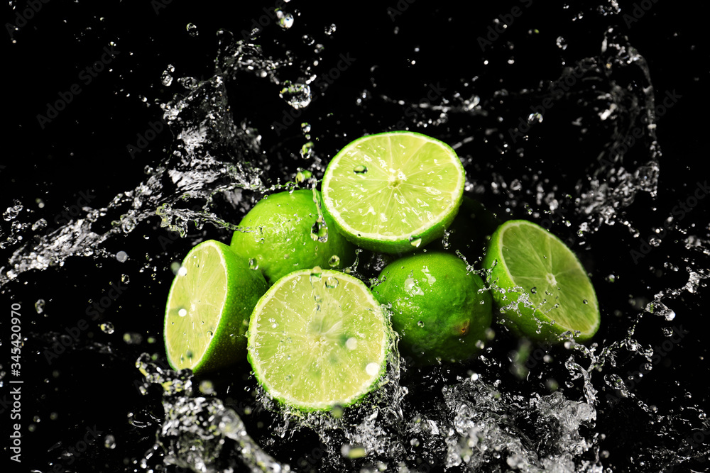 Fresh limes with water splashes on dark background