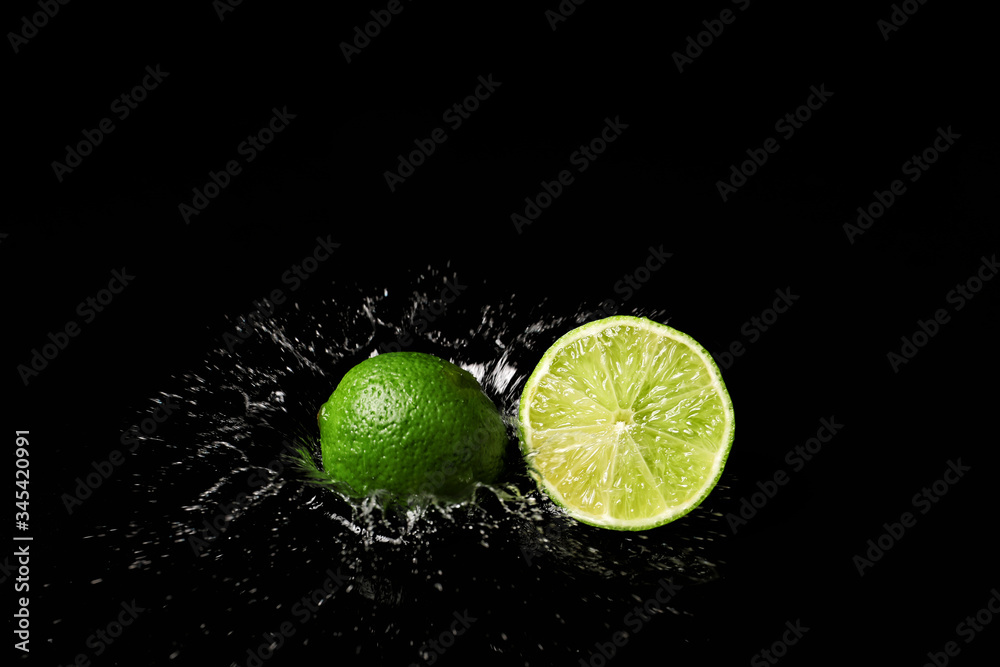 Fresh limes with water splashes on dark background