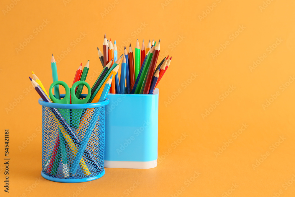 Holders with stationery on color background