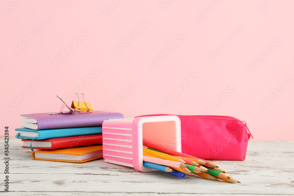 Holder with stationery on table against color background