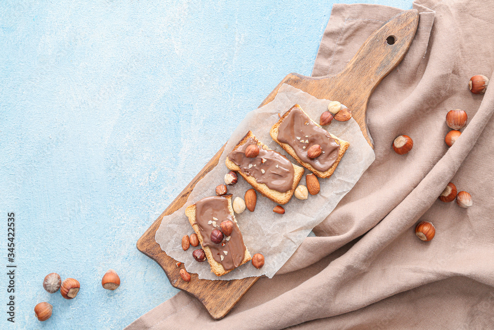 Board with fresh bread and chocolate paste on color background