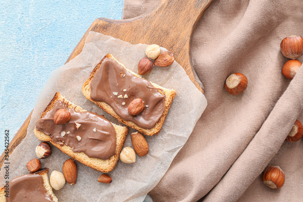 Board with fresh bread and chocolate paste on color background