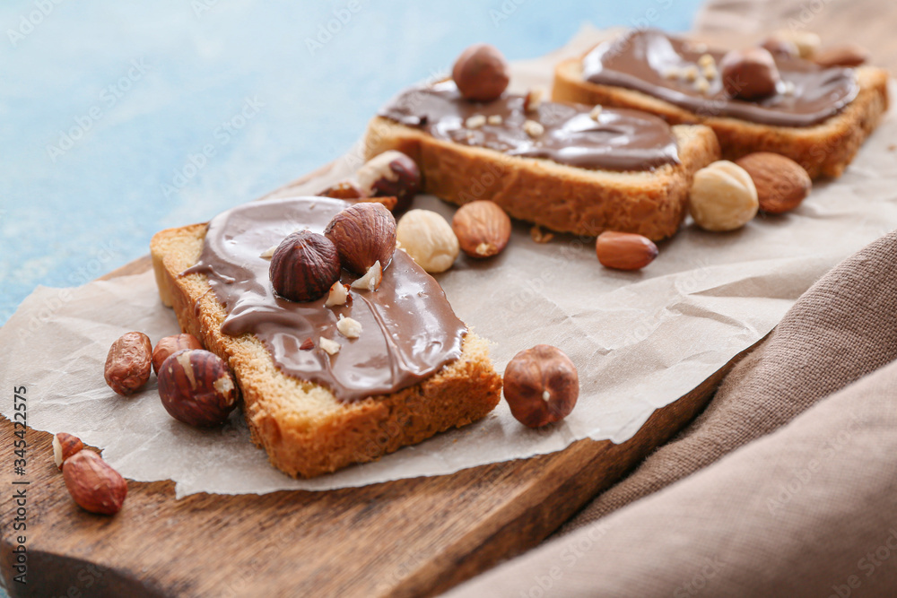 Fresh bread and chocolate paste and nuts on board, closeup