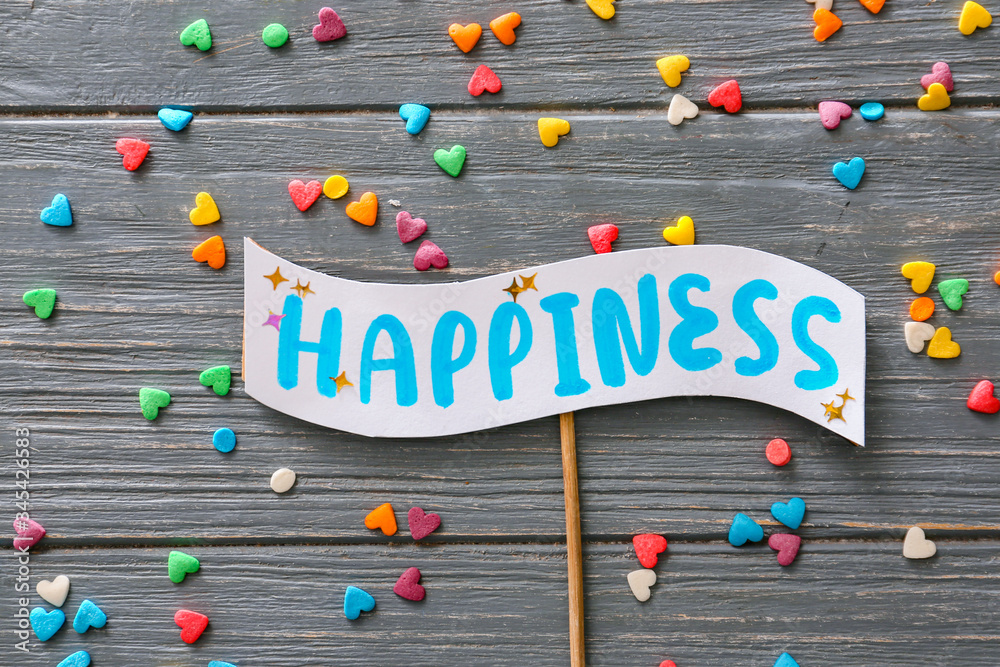 Stick with word HAPPINESS on wooden background