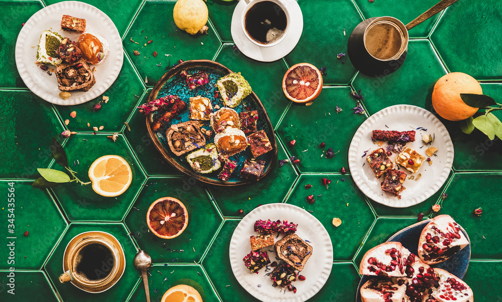 Flat-lay of variety of Turkish traditional lokum sweet delight with Turkish coffee in cups over gree