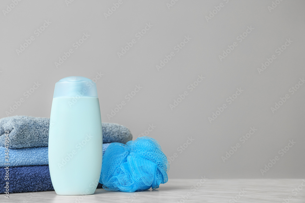 Shower gel, towels and loofah on grey background