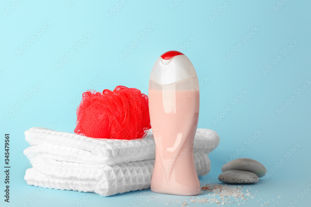 Shower gel, towel and loofah on color background