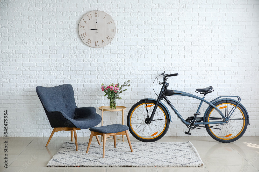 Interior of modern living room with comfortable armchair, table and bicycle