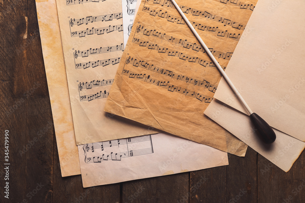 Note sheets and conductors stick on wooden background