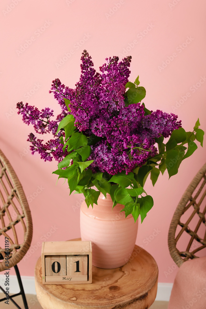 Beautiful lilac flowers with calendar on table in room