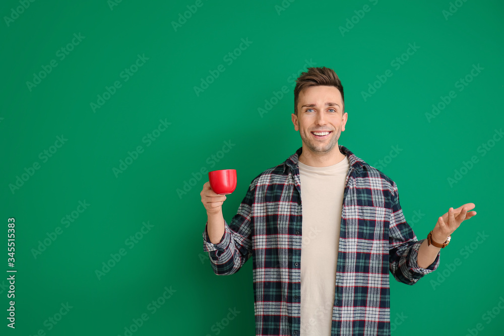 Young man with coffee on color background