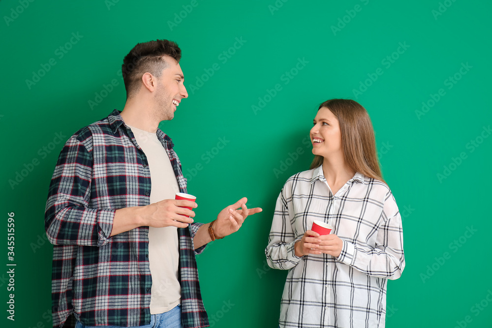 Young couple with coffee on color background