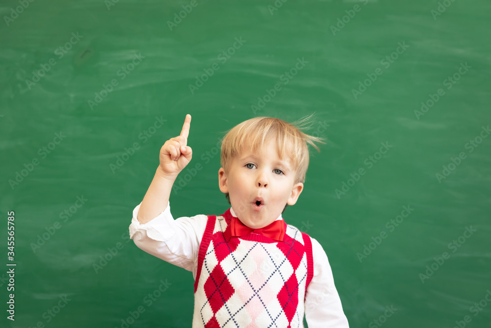 Bright idea! Happy child student against green chalkboard