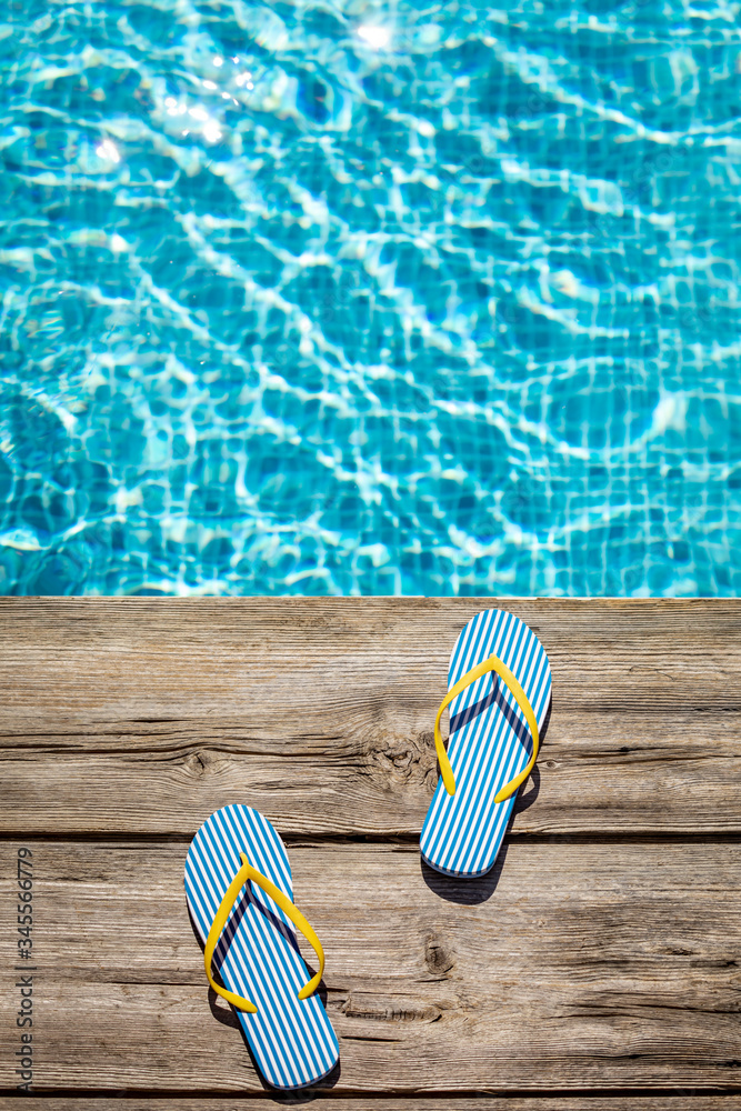 Flip-flops on wooden background near swimming pool