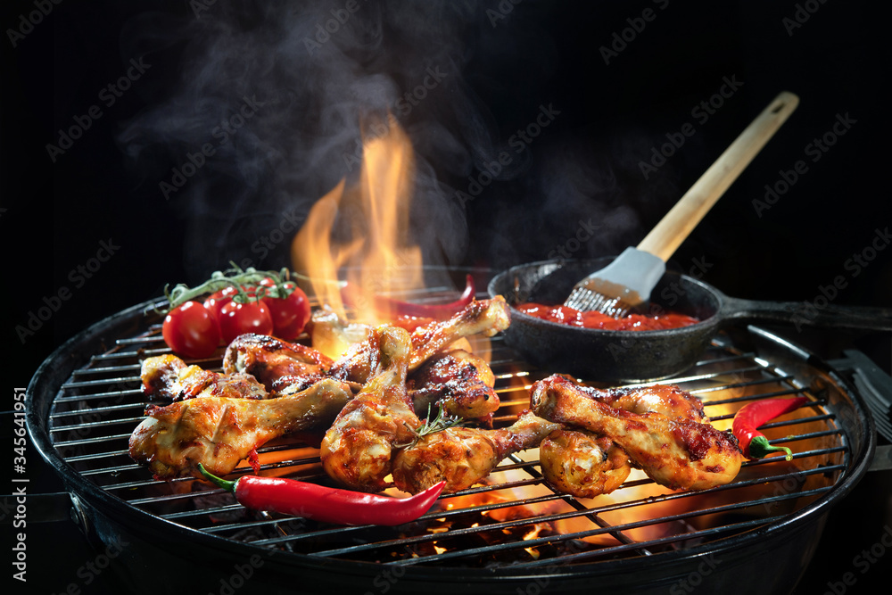 Grilled chicken legs or drumsticks on the hot flaming grill