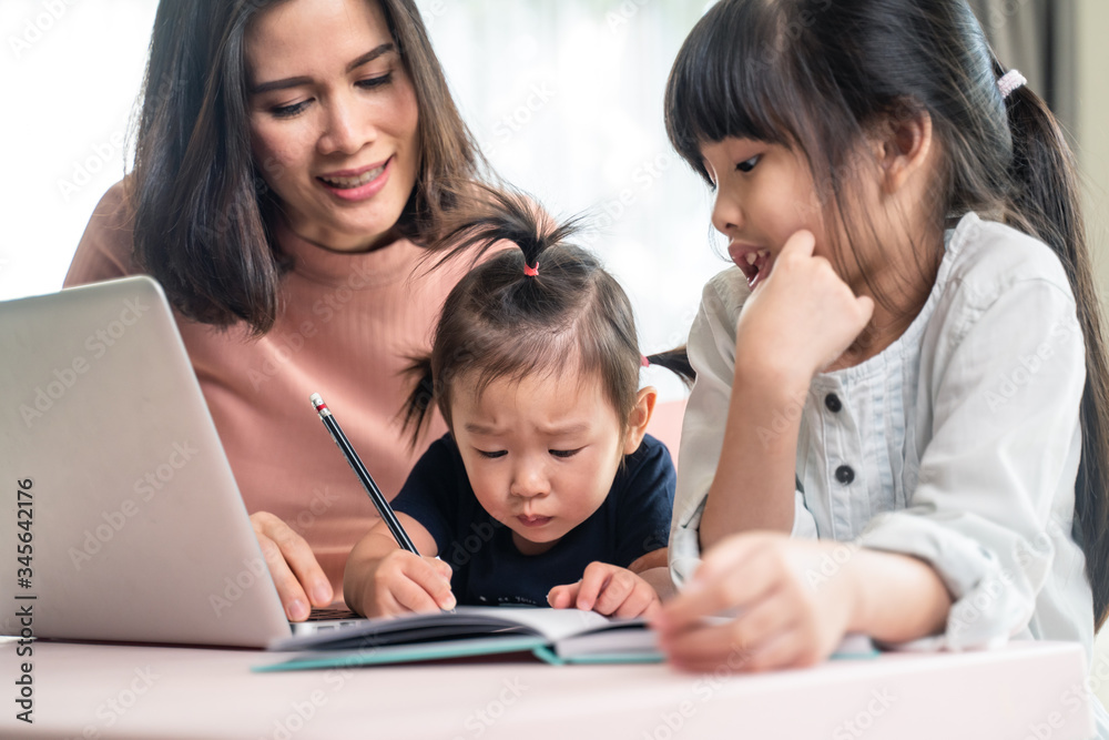 Asian young children learning internet online from home with mother.