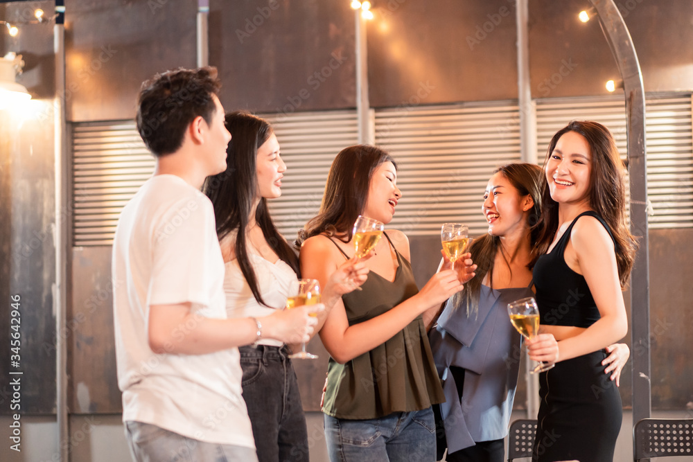 Group of young cute Asian man and woman friends having party at rooftop restaurant. Girls drinking b