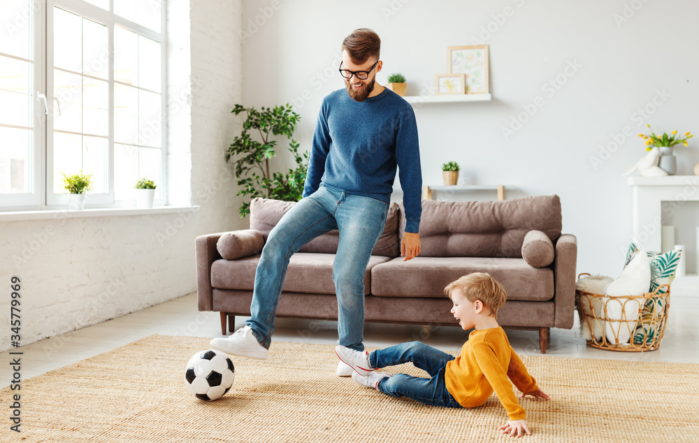 Father and son playing football in cozy room