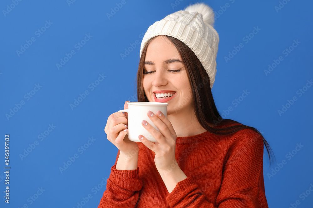 Beautiful young woman with cup of hot cocoa on color background