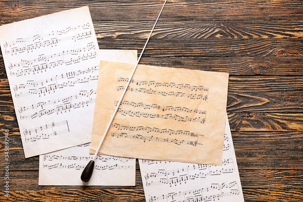 Note sheets and conductors stick on wooden background