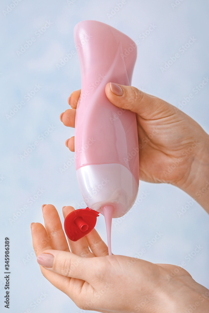 Female hands with shower gel on light background