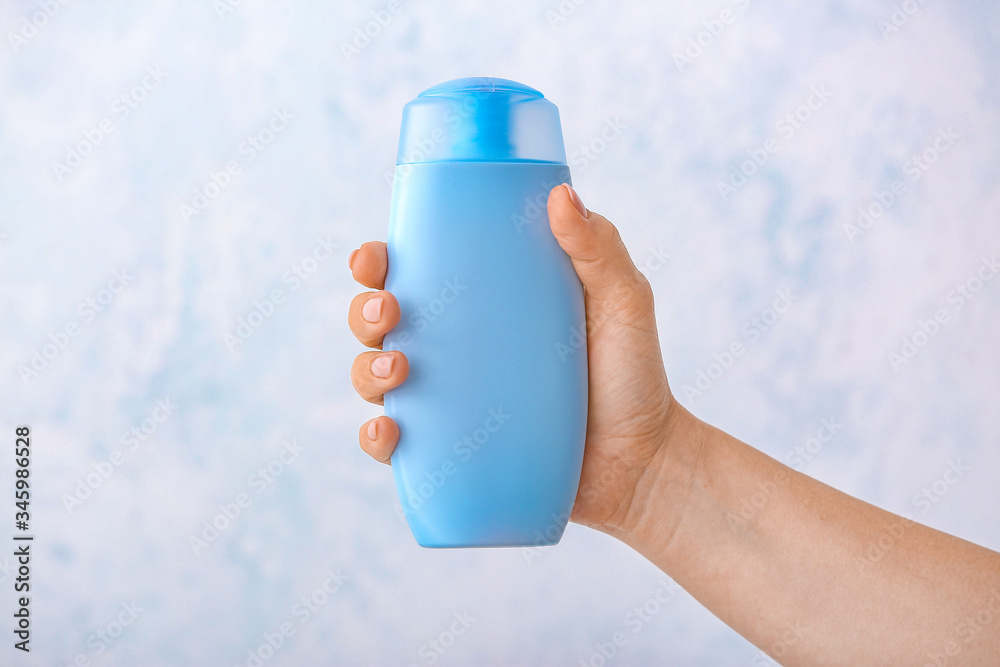 Female hand with shower gel on light background