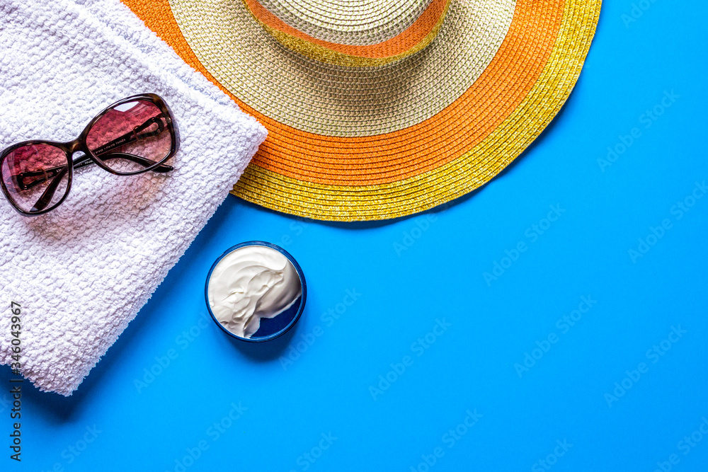 Summer rest with protiction cream, hat, towel blue desk top view space for text